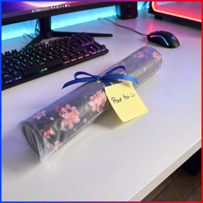 Tapis de souris XXL roulé dans son emballage avec un ruban cadeau bleu et un mot « Pour toi »